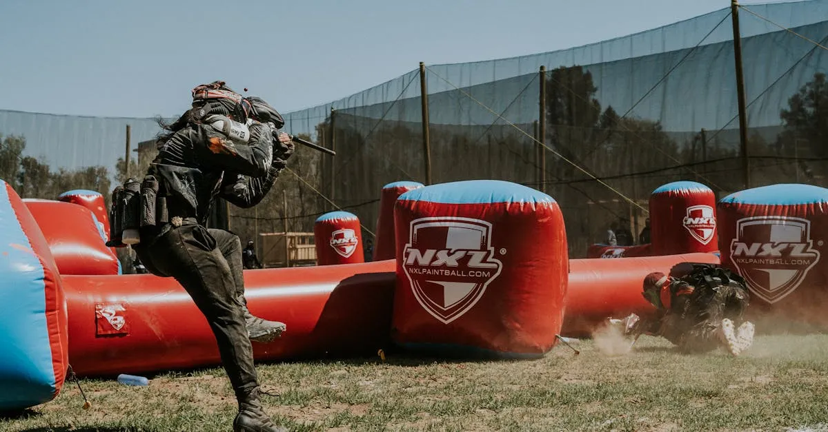 Players competing on a large outdoor paintball field with professional bunkers and obstacles