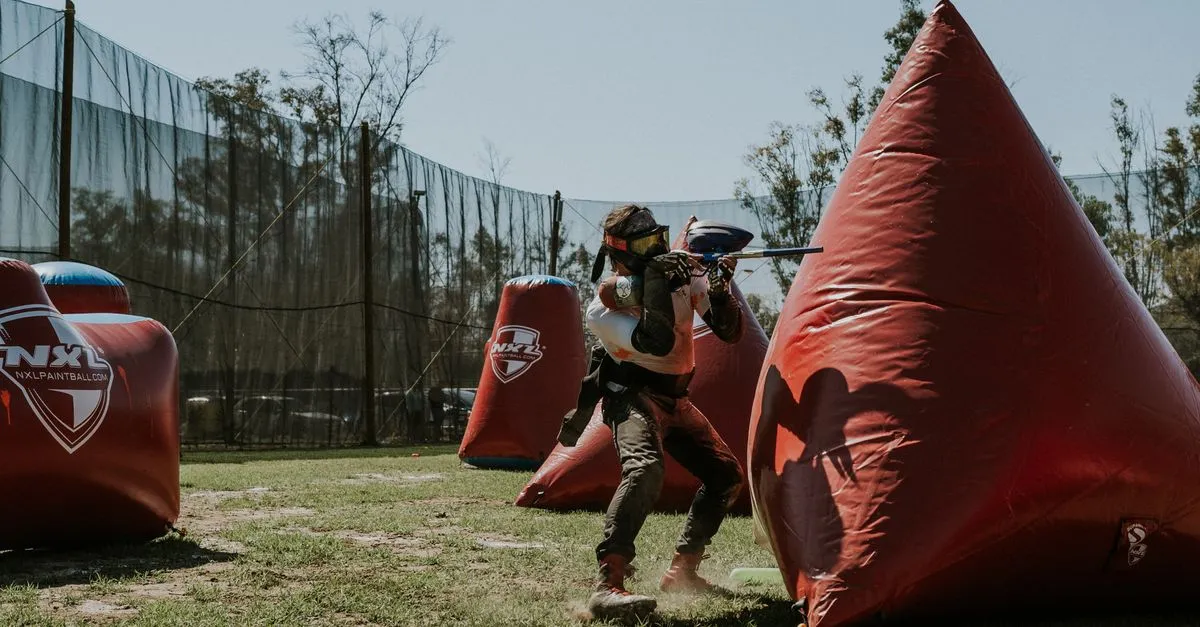 Player aiming from behind an inflatable bunker, the close range where a paintball pistol works best