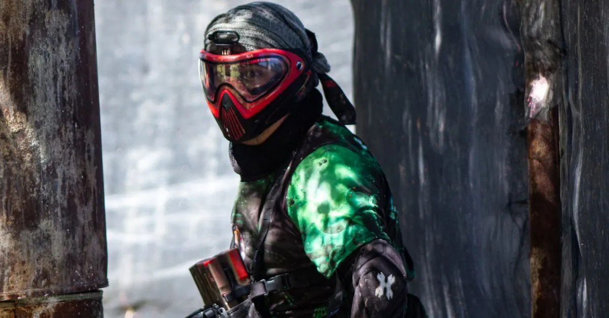 Masked player aiming a marker outdoors, the kind of close-range play suited to a paintball shotgun