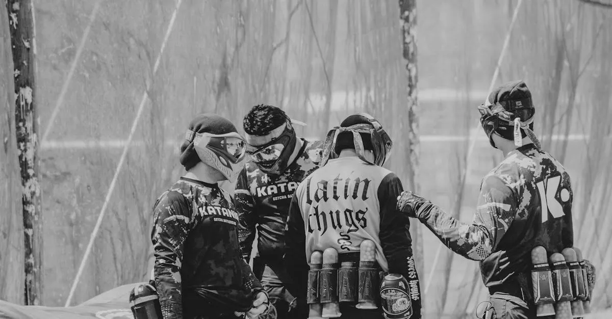 Black and white photo of a paintball team discussing strategy during a game outdoors.